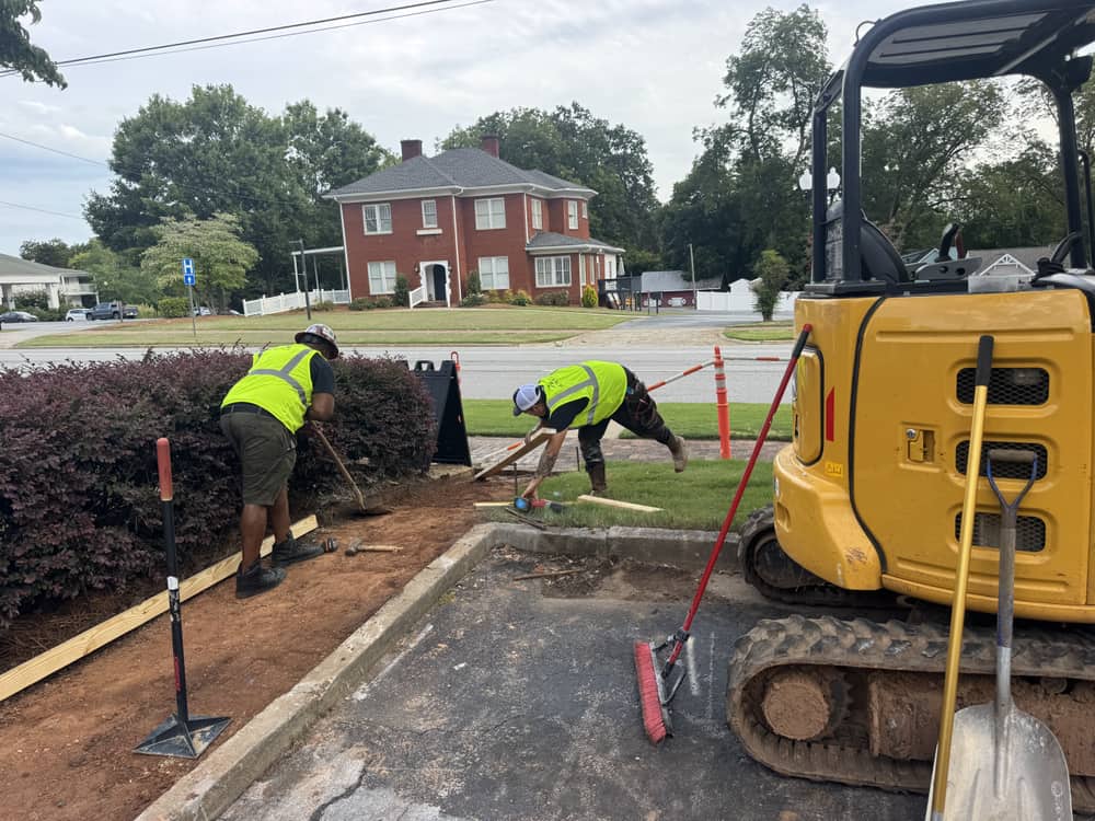 Fenlo crew and mini excavator setting hardscape forms on an active jobsite