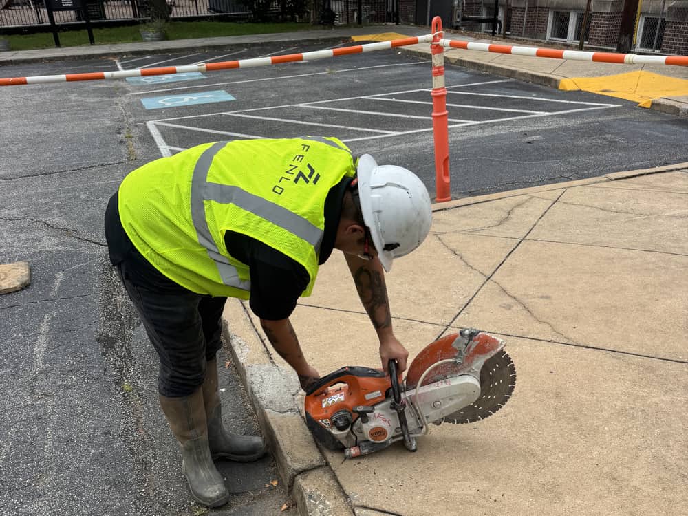 Fenlo crew member in full PPE operating a concrete saw